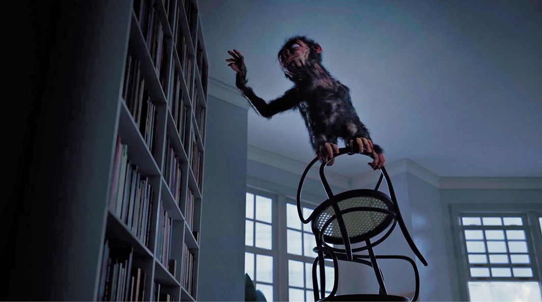 Monkey-like creature balancing on a chair in front of a bookcase