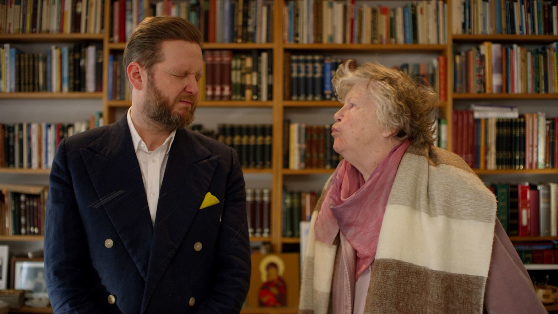 video still of a woman spitting on her son in front of a bookcase