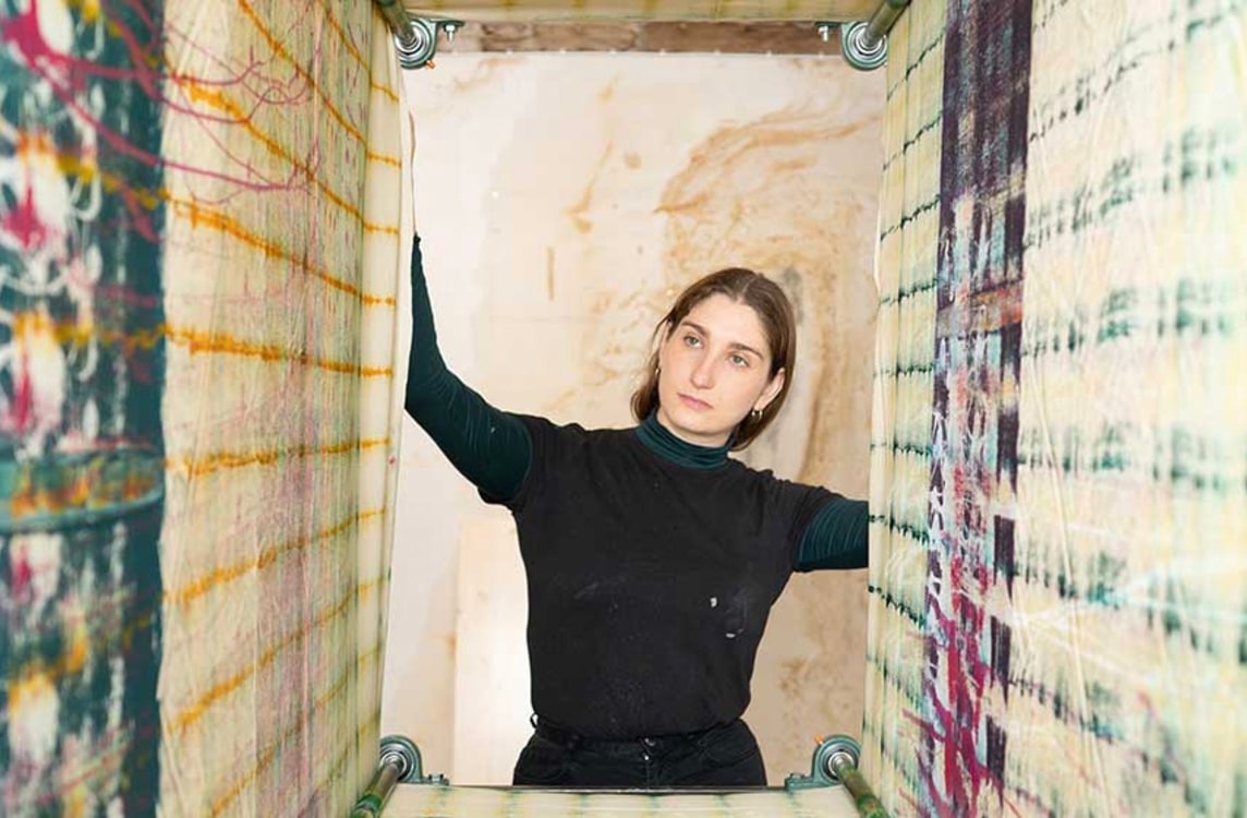 A female artist in her studio with abstract patterned painting