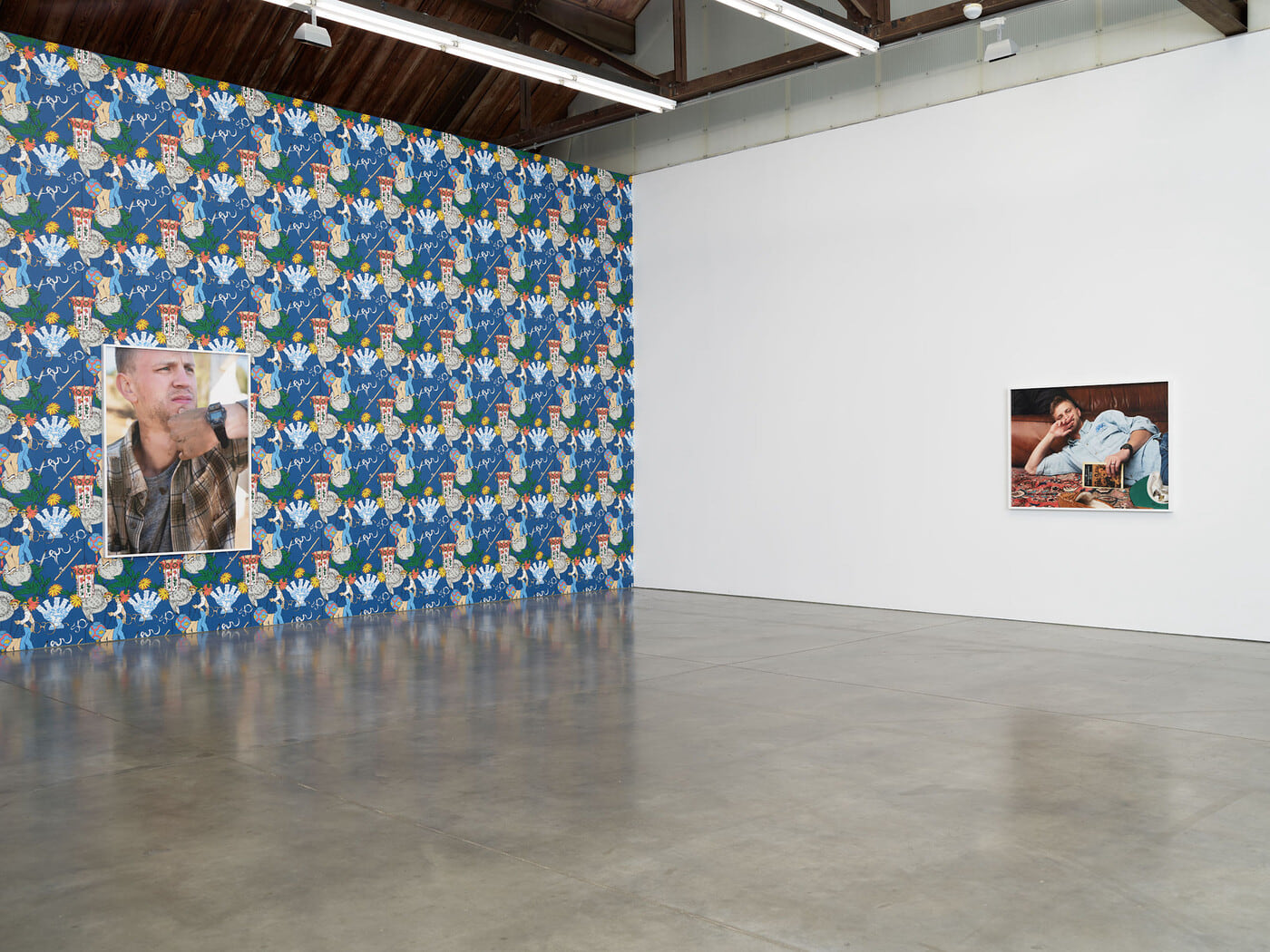 Art gallery with patterned blue wallpaper and 2 photographs of a young white man