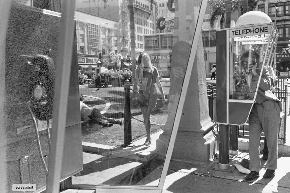 Black and white photograph of 2 telephone booths in an outdoor city square