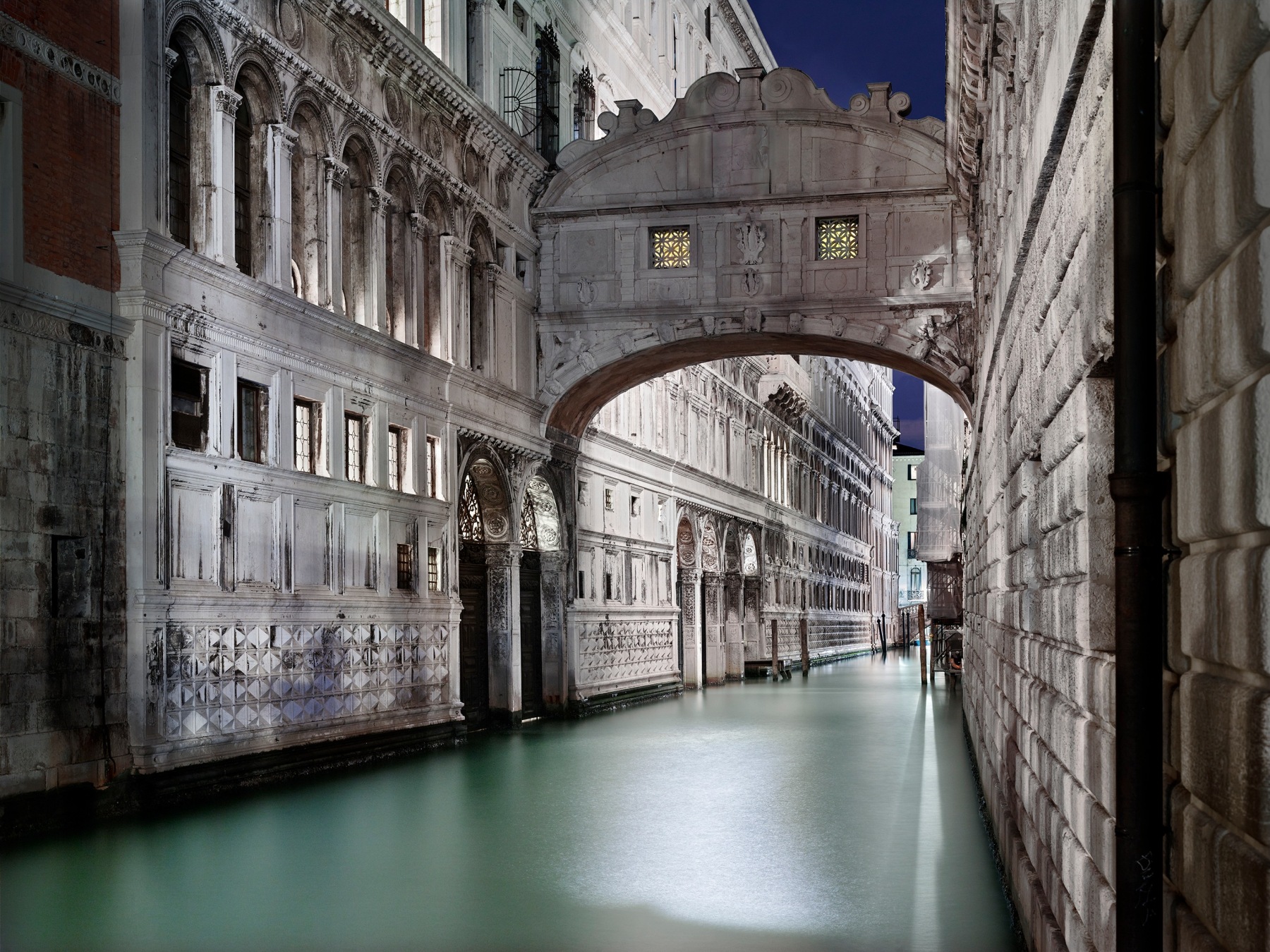 Night photo of a Venice canal with bridge crossing over.