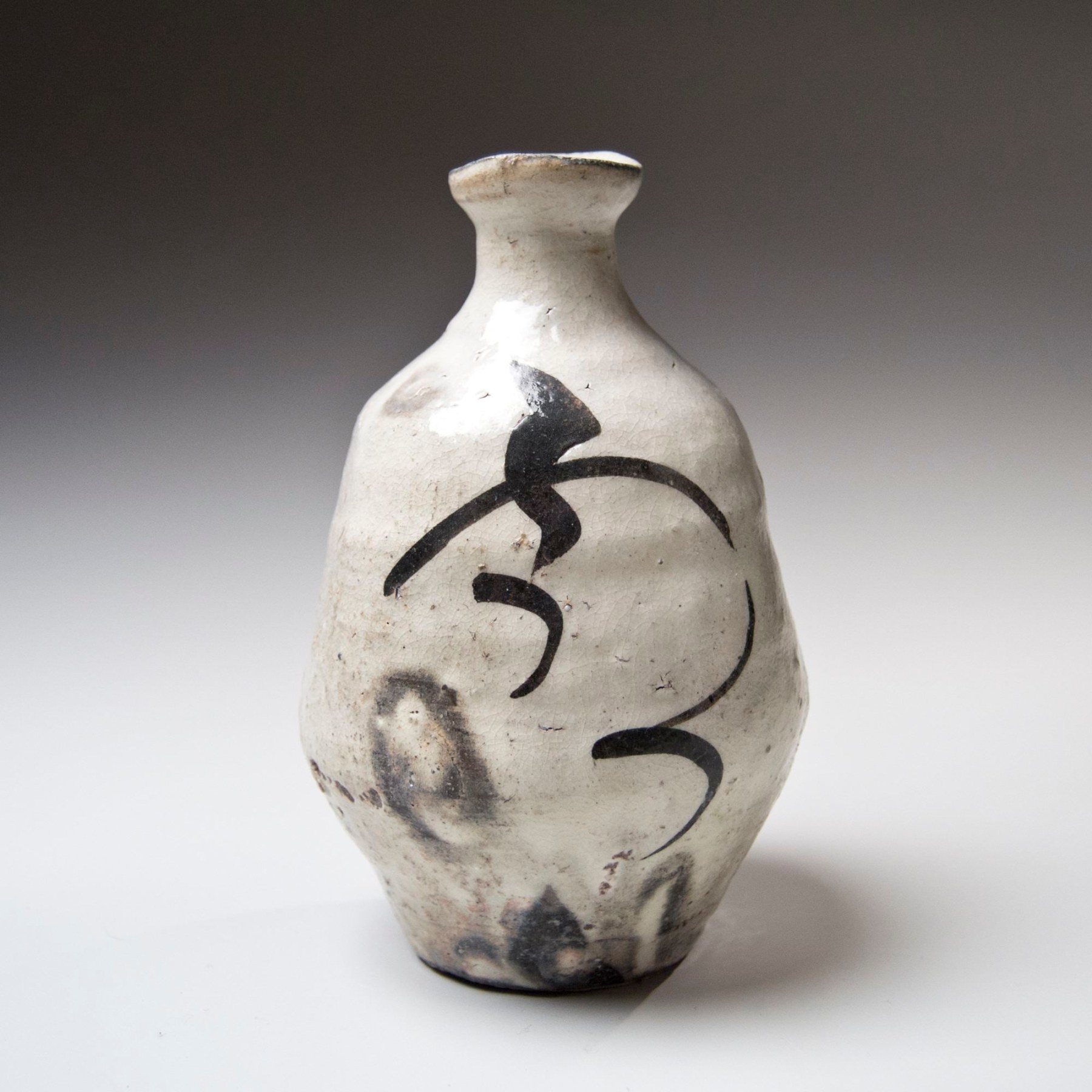 Kawakami Kiyomi (b. 1948), Kohiki-glazed (white slip with translucent overglaze) tokkuri (sake flask) with calligraphic patterning in iron glaze
