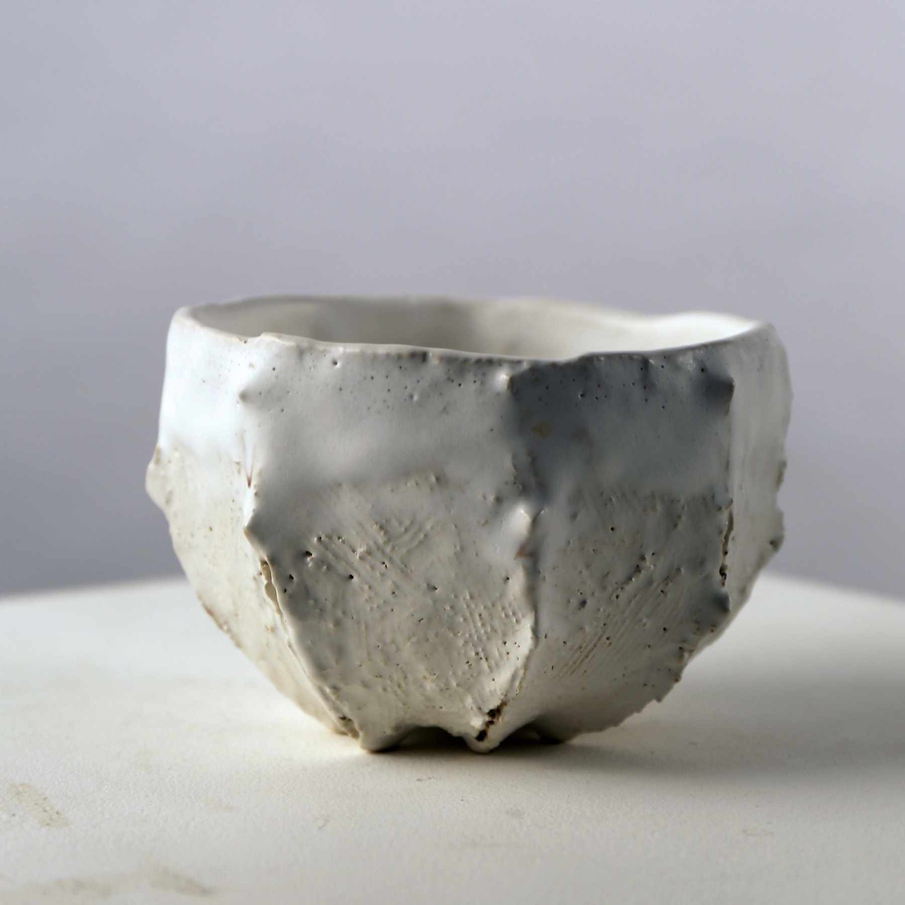 Matte white-glazed ribbed teabowl with small protrusions and interior pool of crackled glaze, 2007