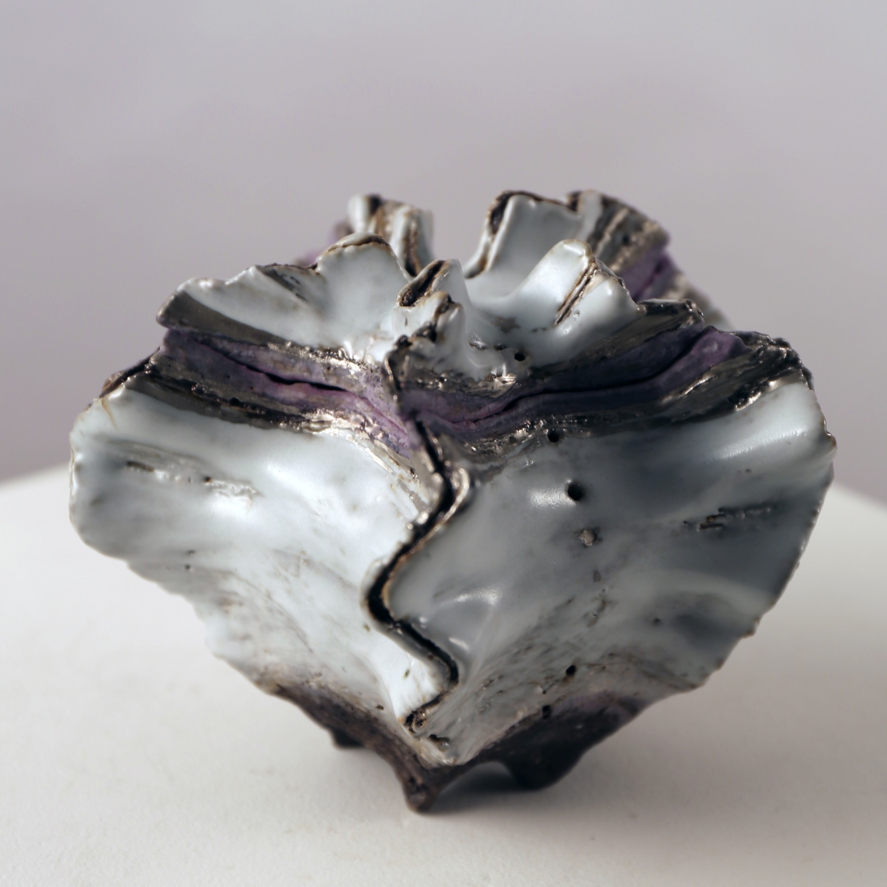 Small, covered shell-shaped container with purple and silver glazes along the mouth, 2013