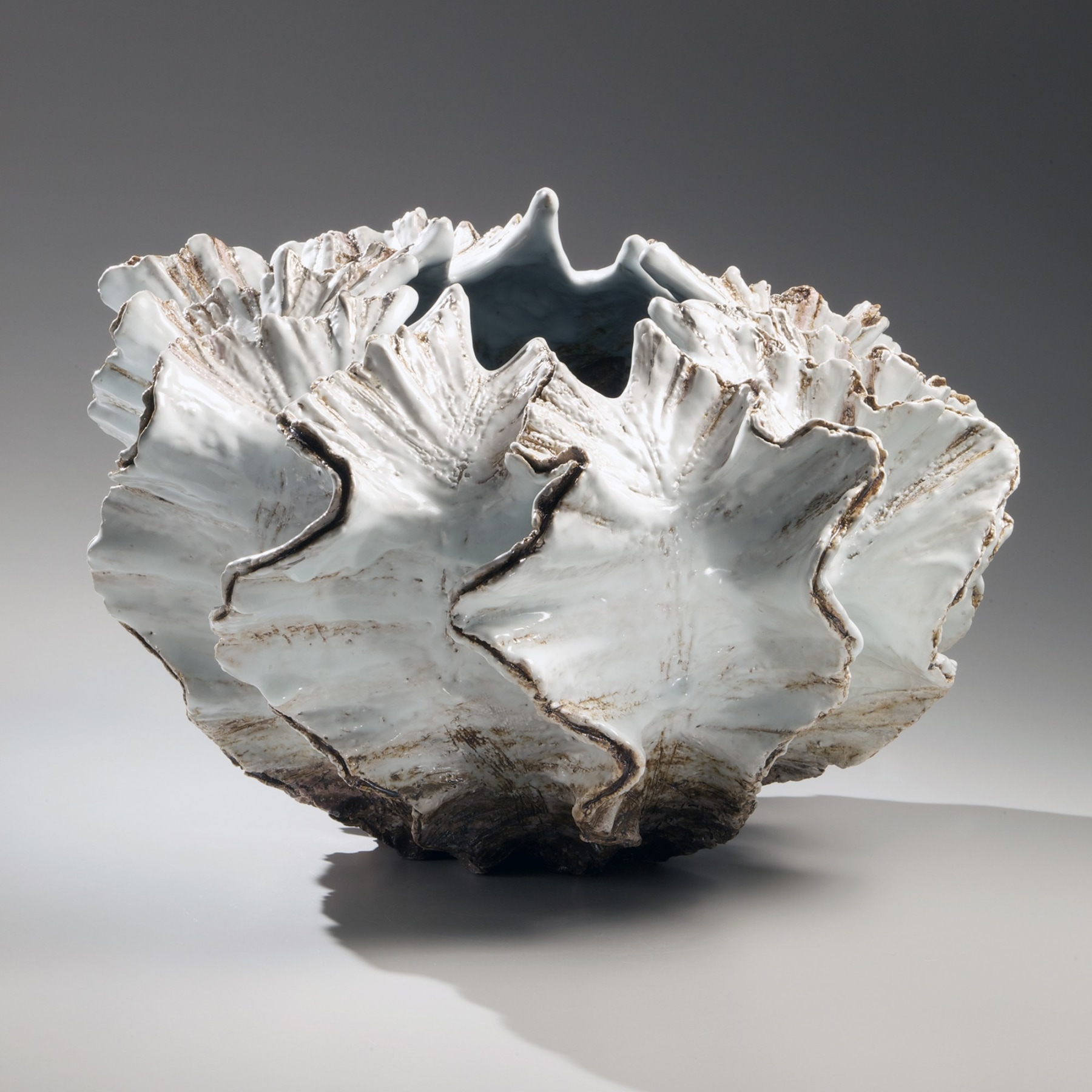 Pleated shell-shaped sculpture with silver glaze along the flaring edges, turquoise and white glazed interior and narrow mouth, 2012