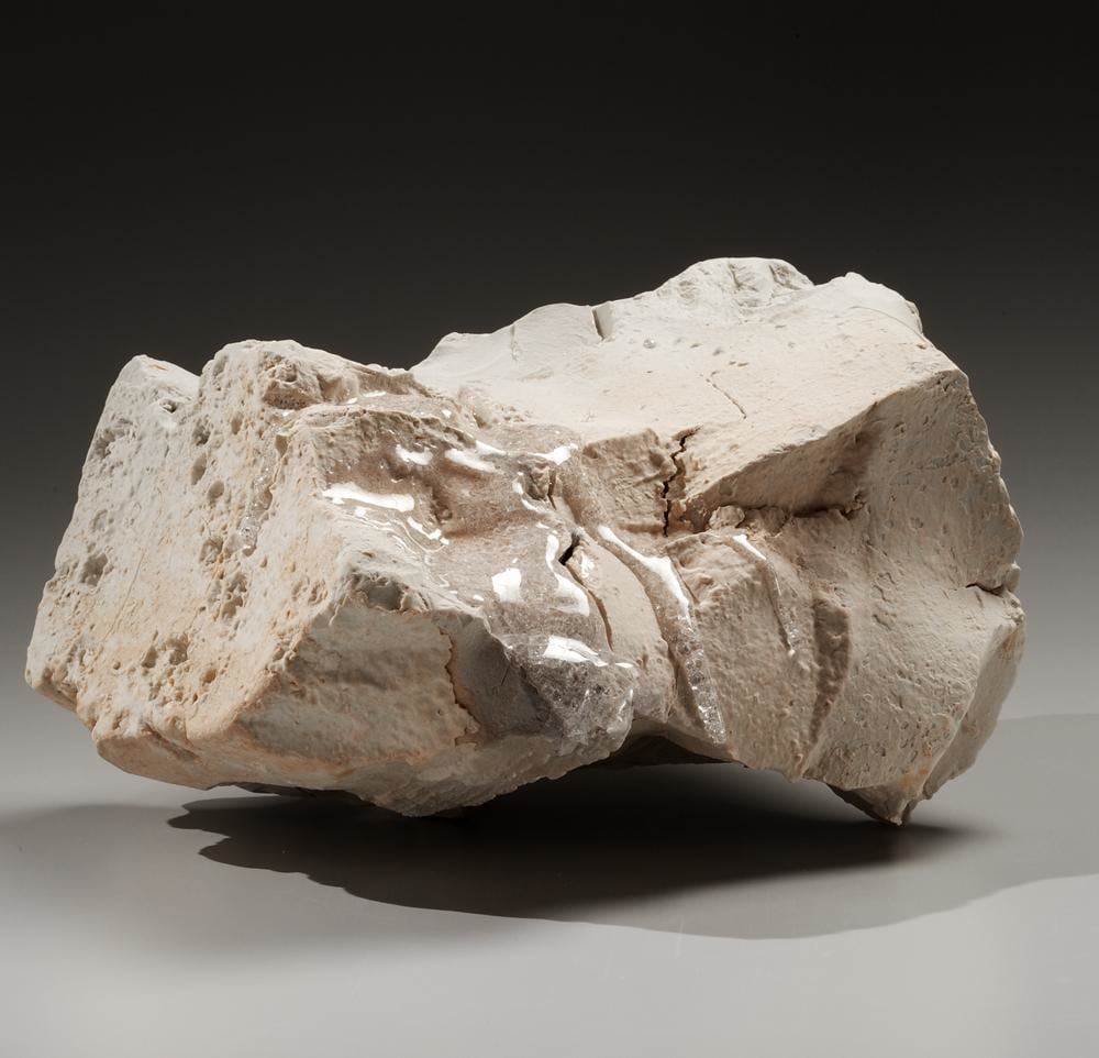 Rock-shaped sculpture with upturned ends in unglazed porcelain and adhered translucent crystalized glass