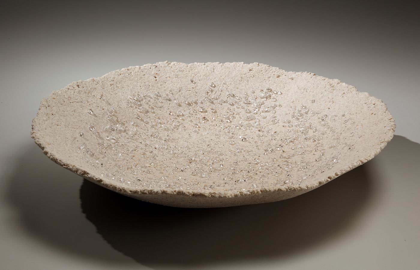 Round platter with scattered clear glass droplets and pinched rough rim