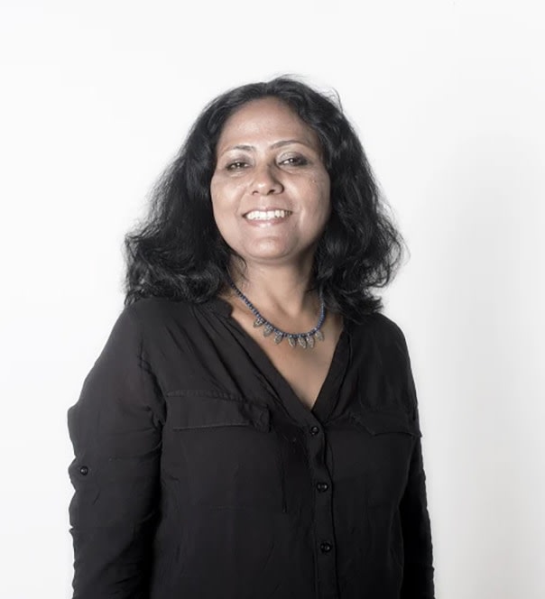 Portrait of artist Tayeba Begum Lipi wearing a black V-neck blouse standing against a white backdrop.