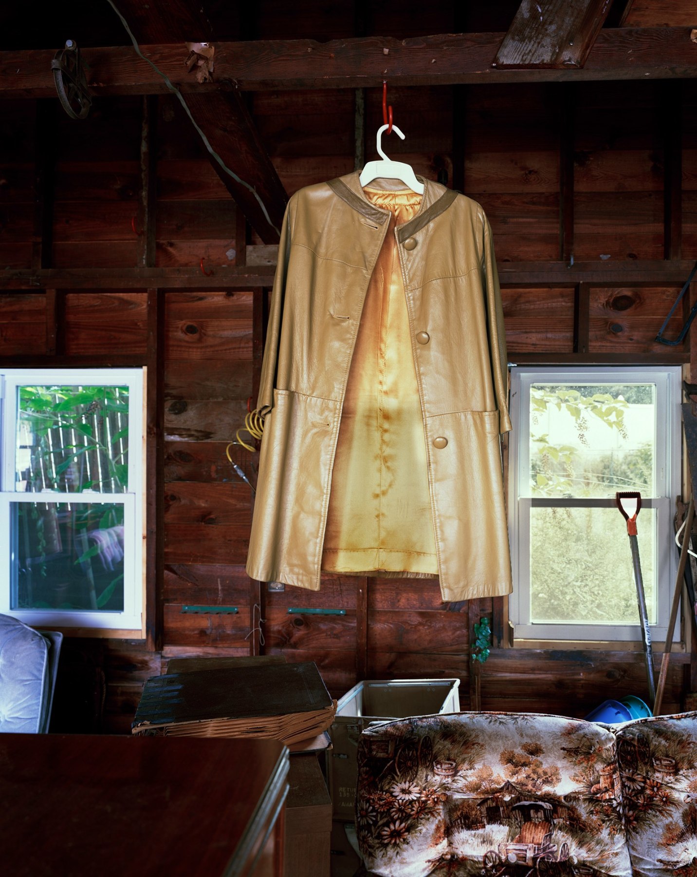 Photograph of leather jacker hanging from rafter in cabin, by Jade Doskow