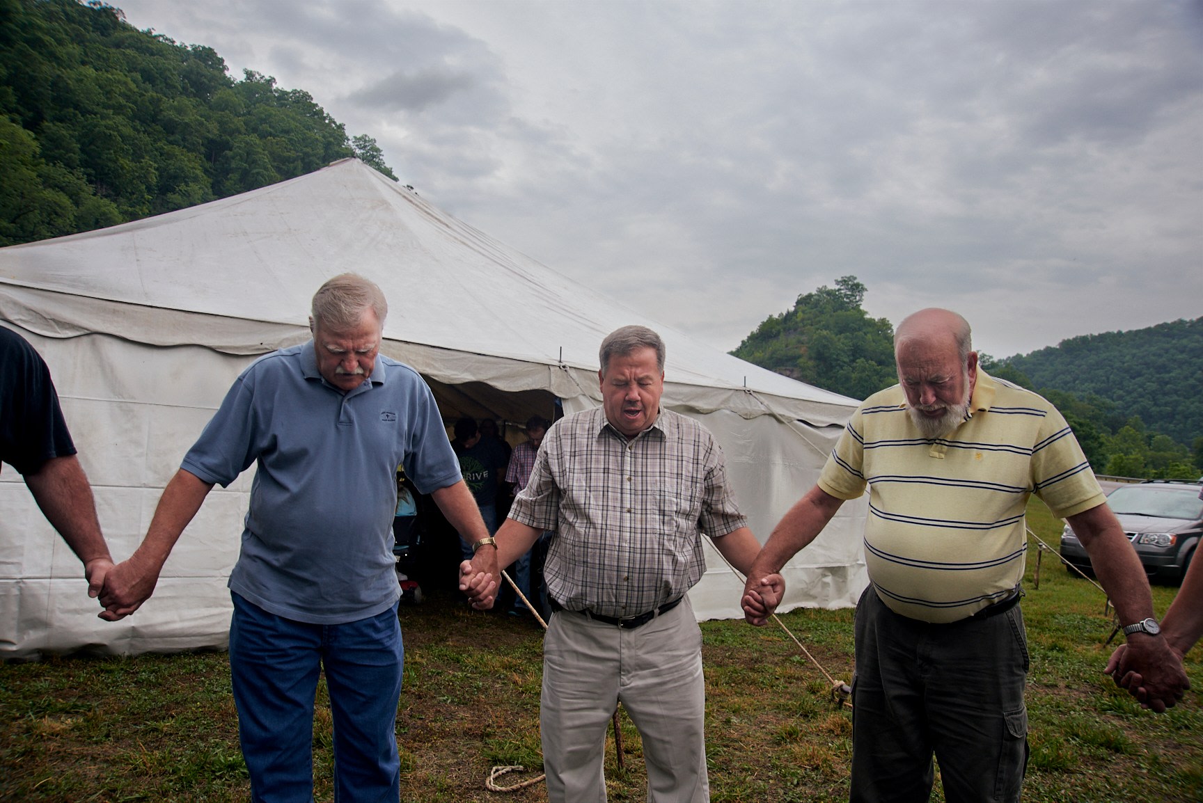 Stacy Kranitz  Pikeville, Kentcuky, 2015  Archival Pigment Print  16 x 24 inches, Edition of 7  27 x 40 inches, Edition of 3, Men holding hands in a prayer circle.