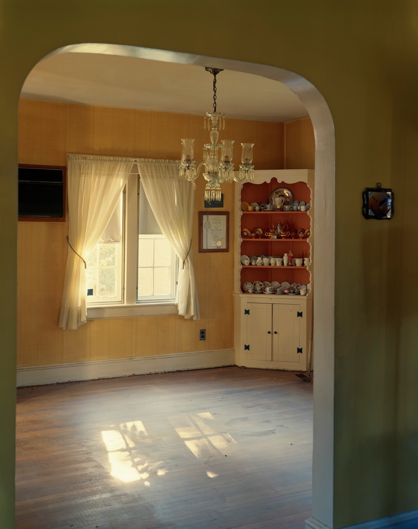 Photograph of empty dinning room with sunlight and arched doorway, by Jade Doskow