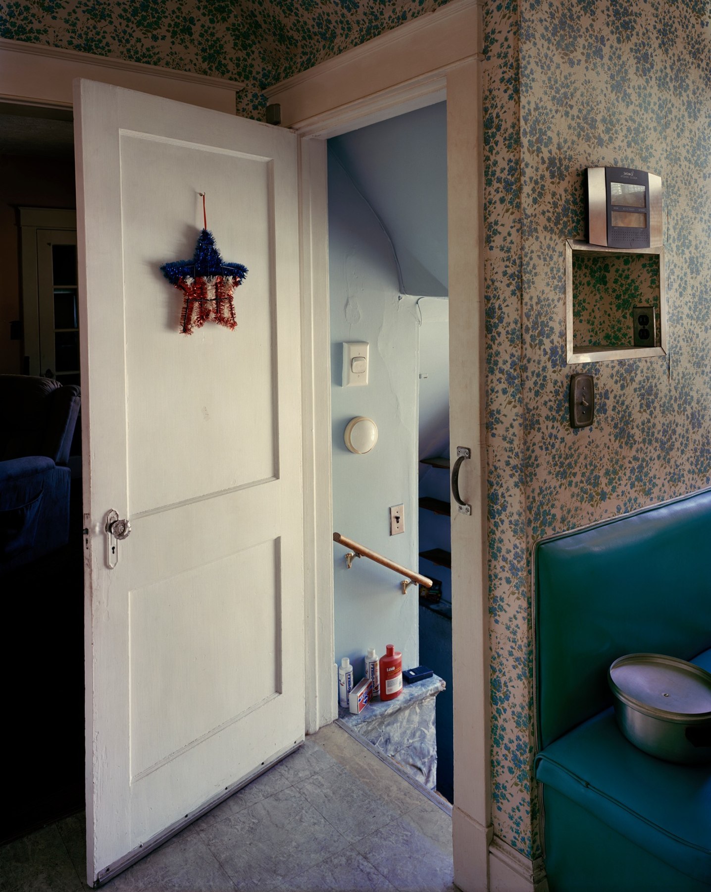Photograph of interior or house with patterned wallpaper, open door and hanging star, by Jade Doskow