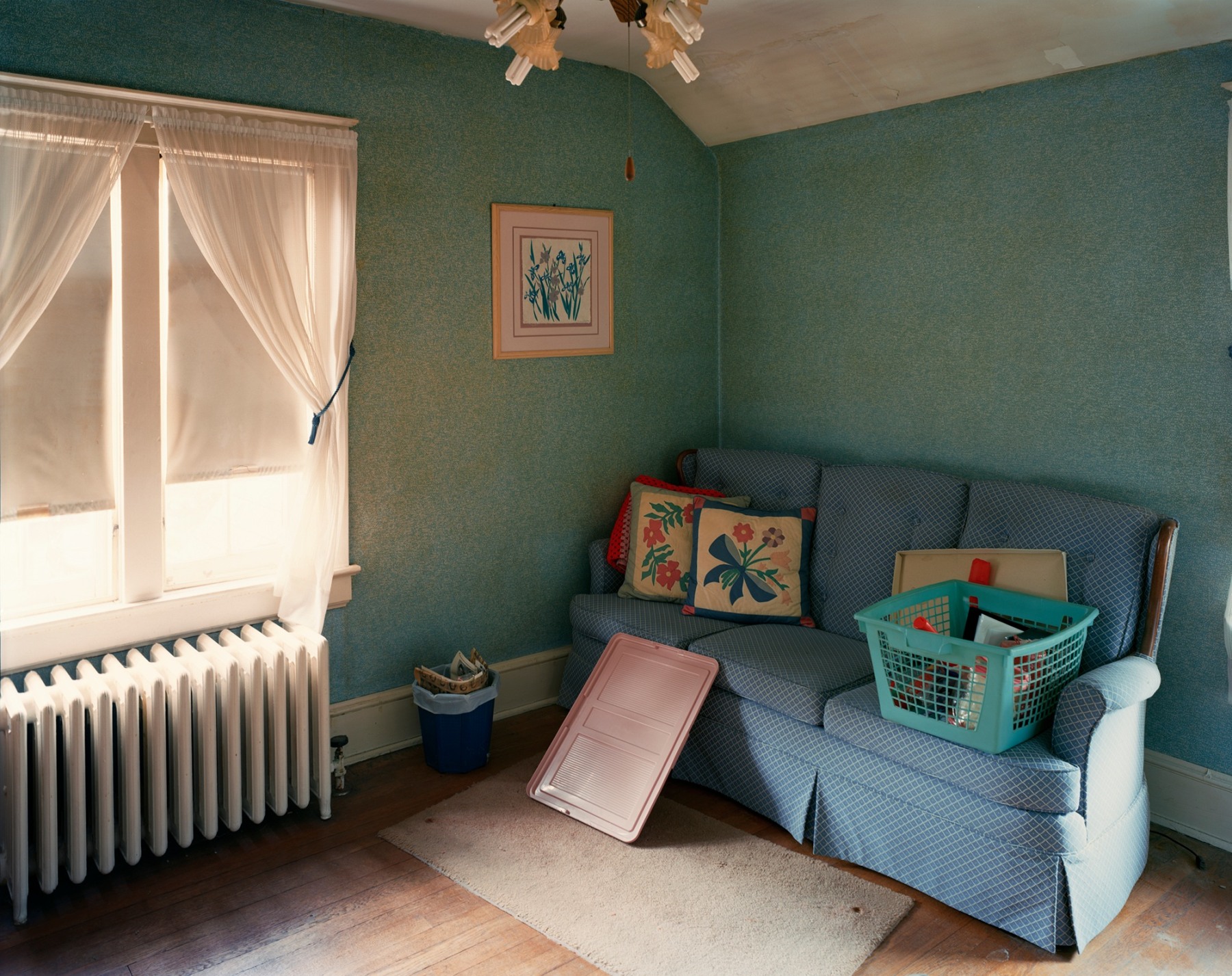 Photograph of den with radiator and blue couch, by Jade Doskow