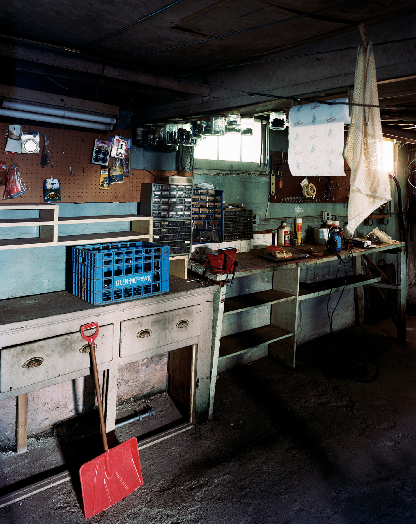 Color photograph of basement workshop area with red shovel, by Jade Doskow