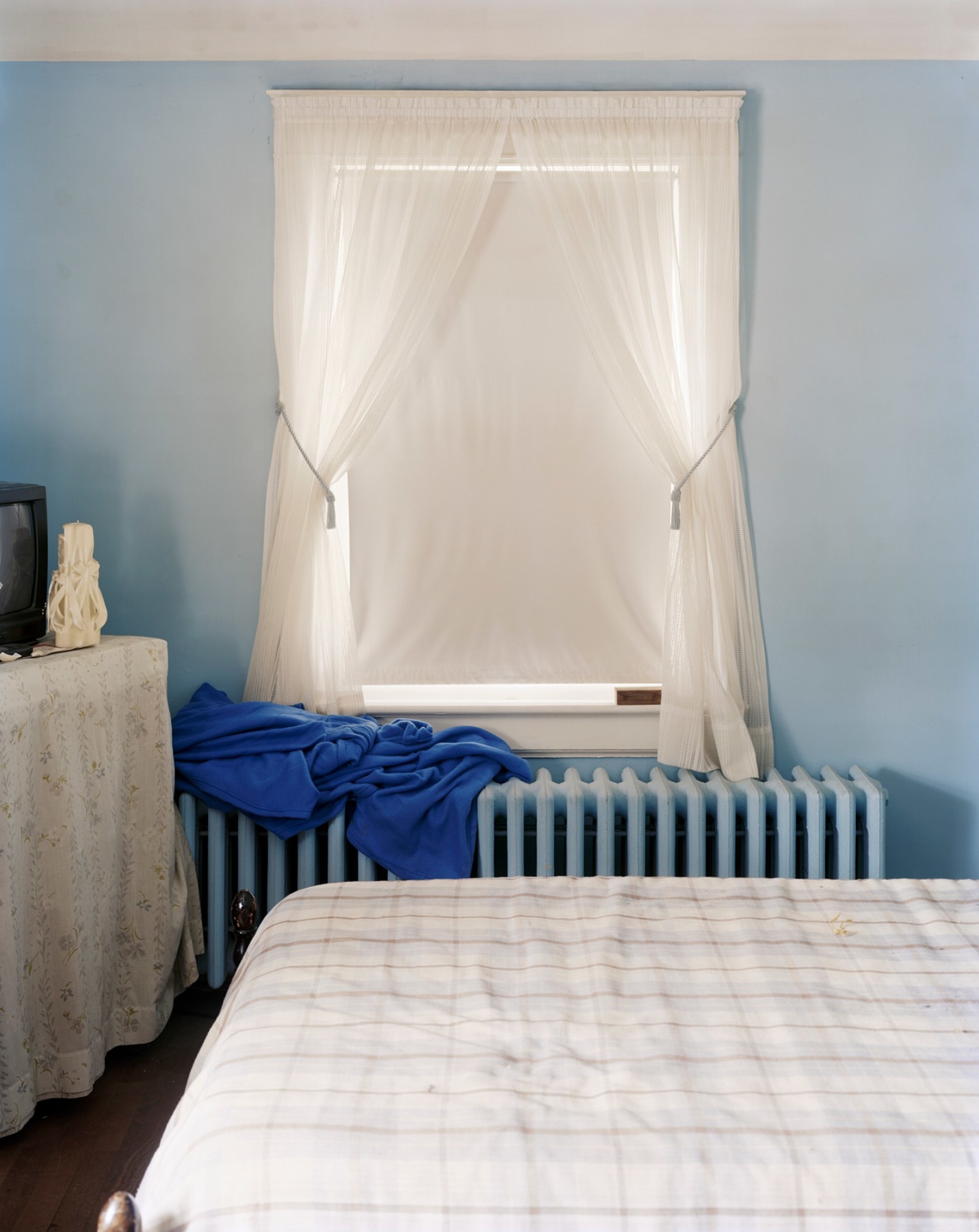 Color photograph of bedroom with blue walls and radiator