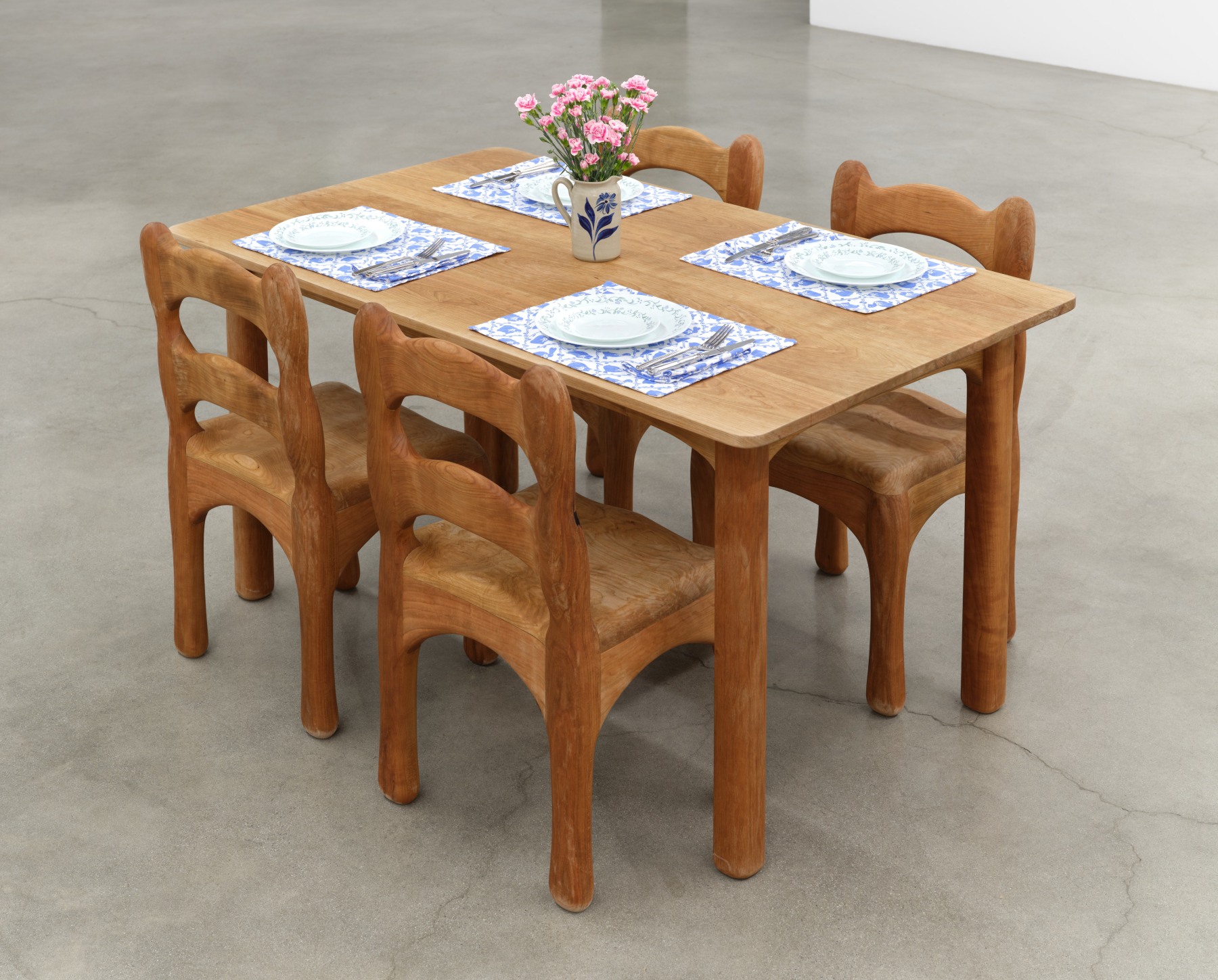 Bambou Gili's artwork "Those Black-Eyed Peas They Tasted Alright to Me, Earl". Four chairs around a set table. 60 x 36 x 30 in (152.4 x 91.4 x 76.2 cm), cherry wood, found objects, 2023.