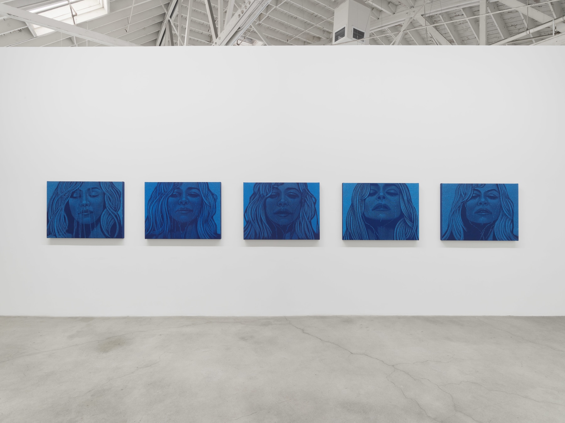 Installation view of Amy Adler's "Audition" at Night Gallery with five blue oil pastel paintings a woman with liquid streaming down her face. 