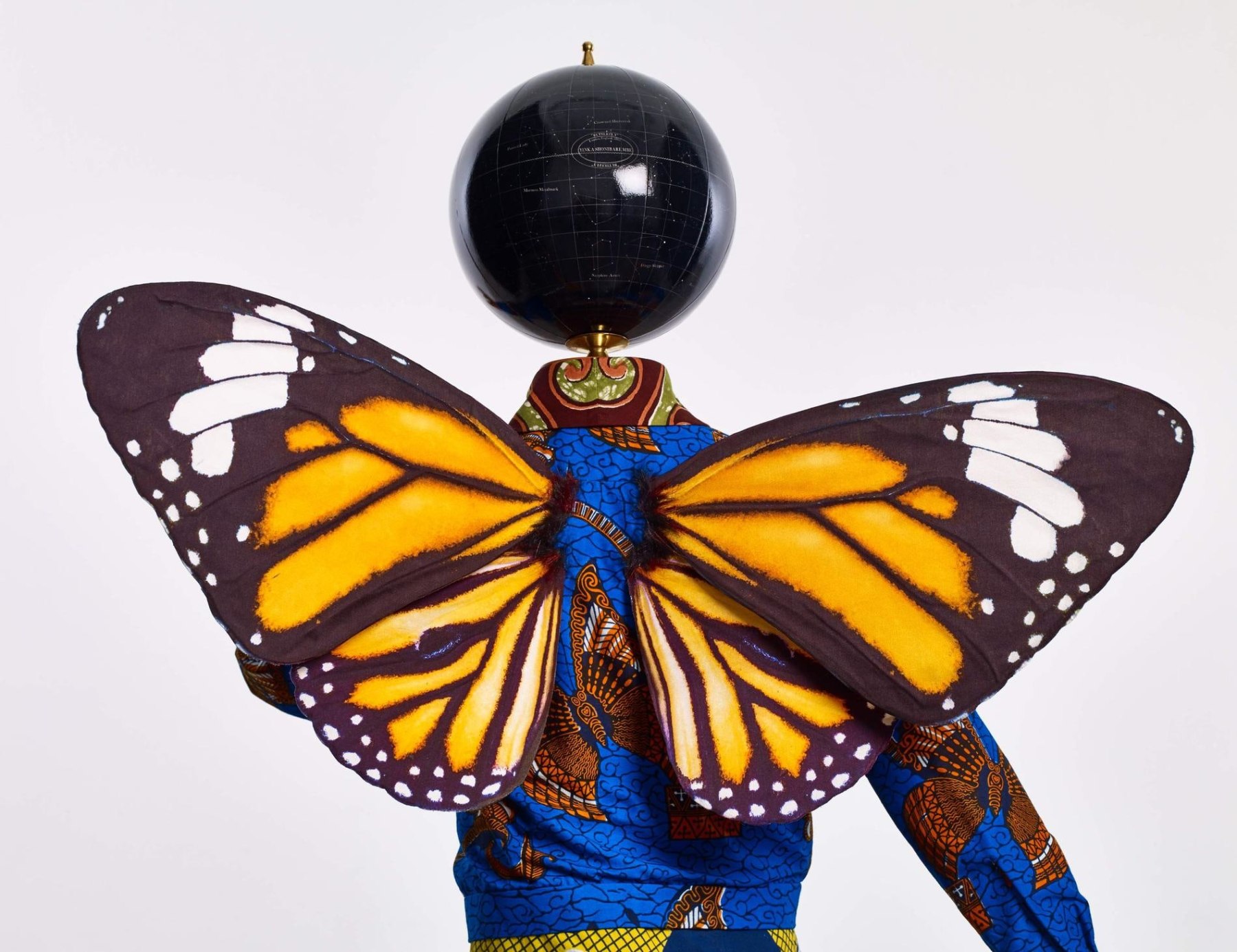 monarch butterfly wings on a mannequin with a globe for a head