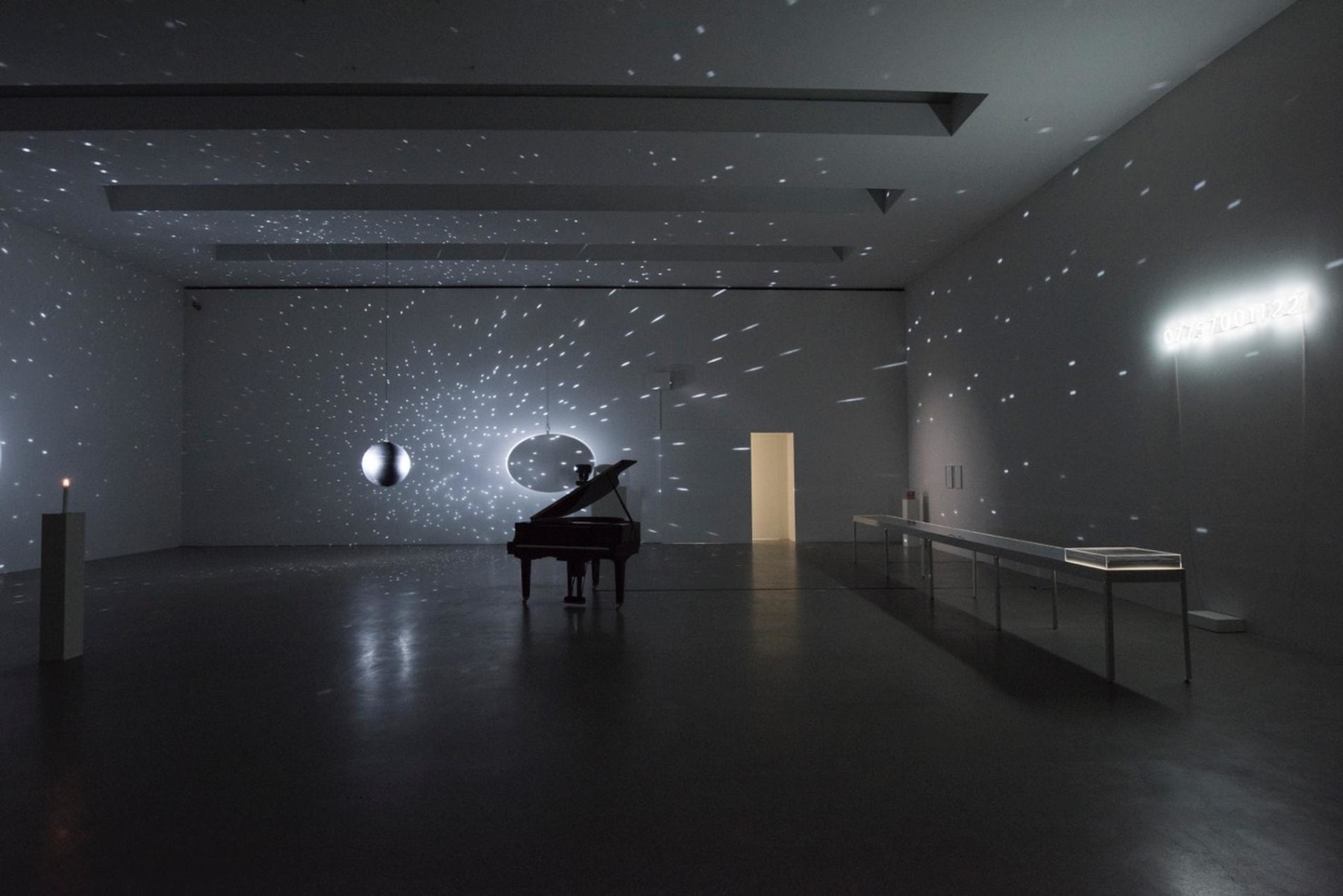 dark room with lights being flashed by a mirrorball, piano in the center