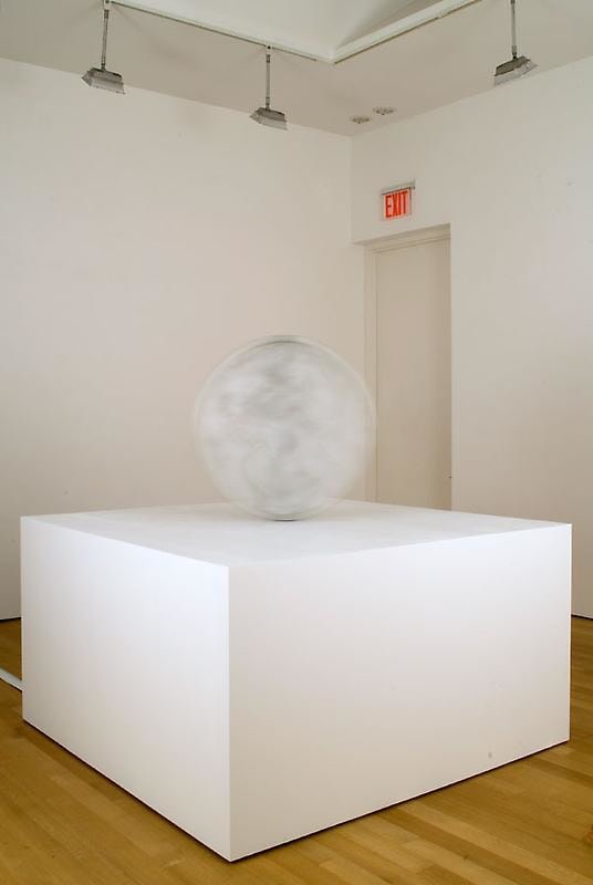 A large aluminum sculpture that resembles a coin in motion