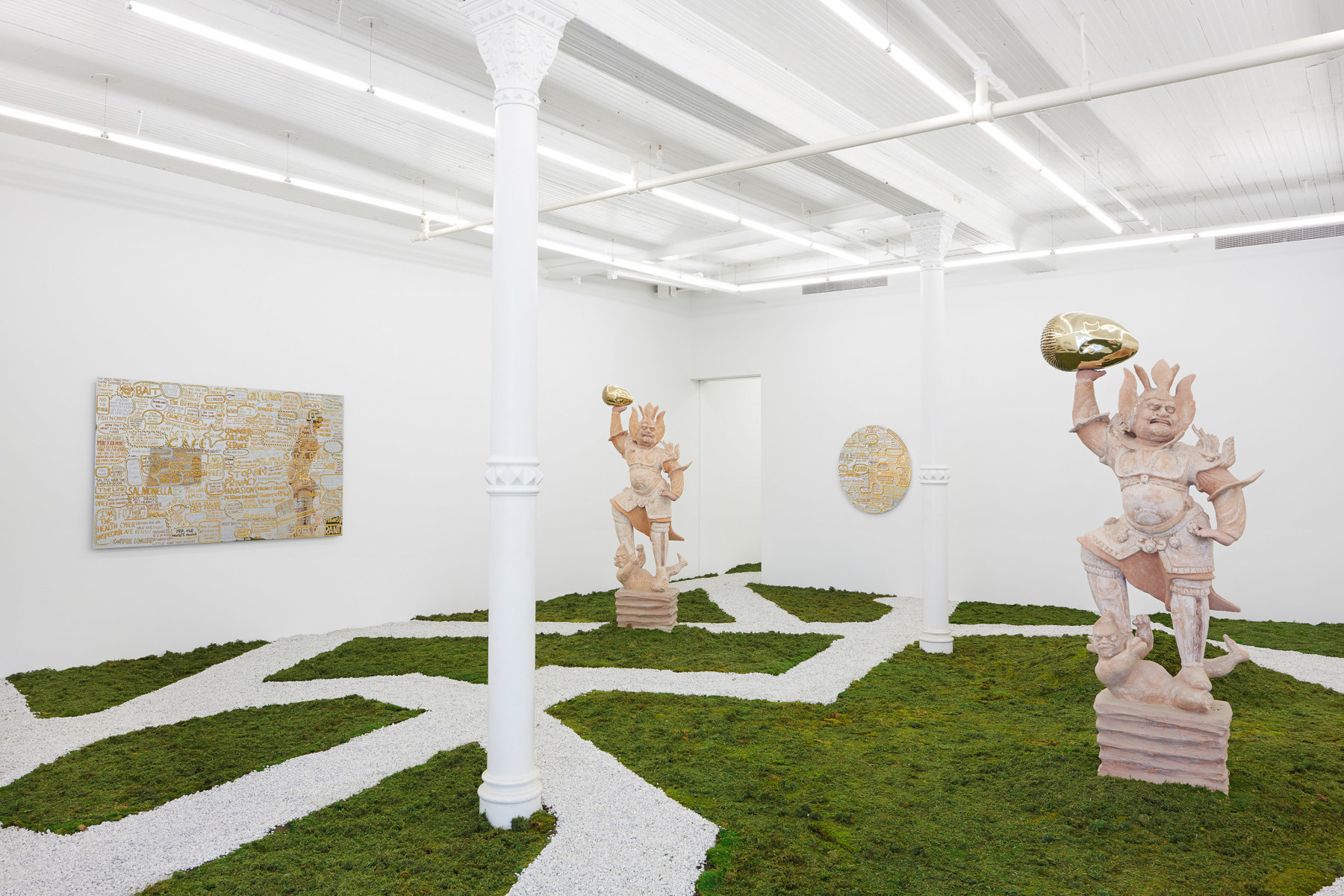 interior space with grass and patches, two bronze sculptures, and two mirror artworks