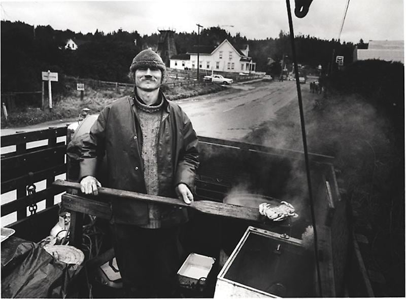 grayscale image of a man boiling crabs in the back of a truck
