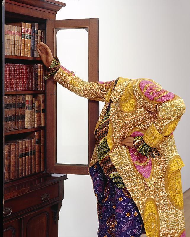 mannequin in a gold jacket reaching for books