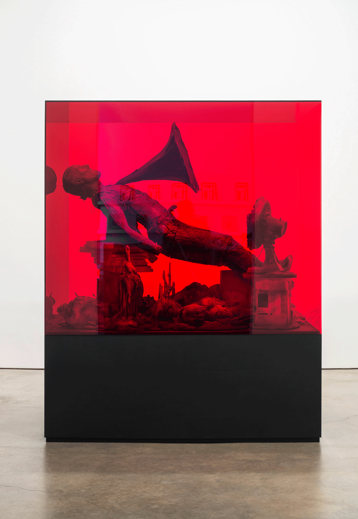 sculpture of a man with airhorn coming out of his chest encased in red tinted glass