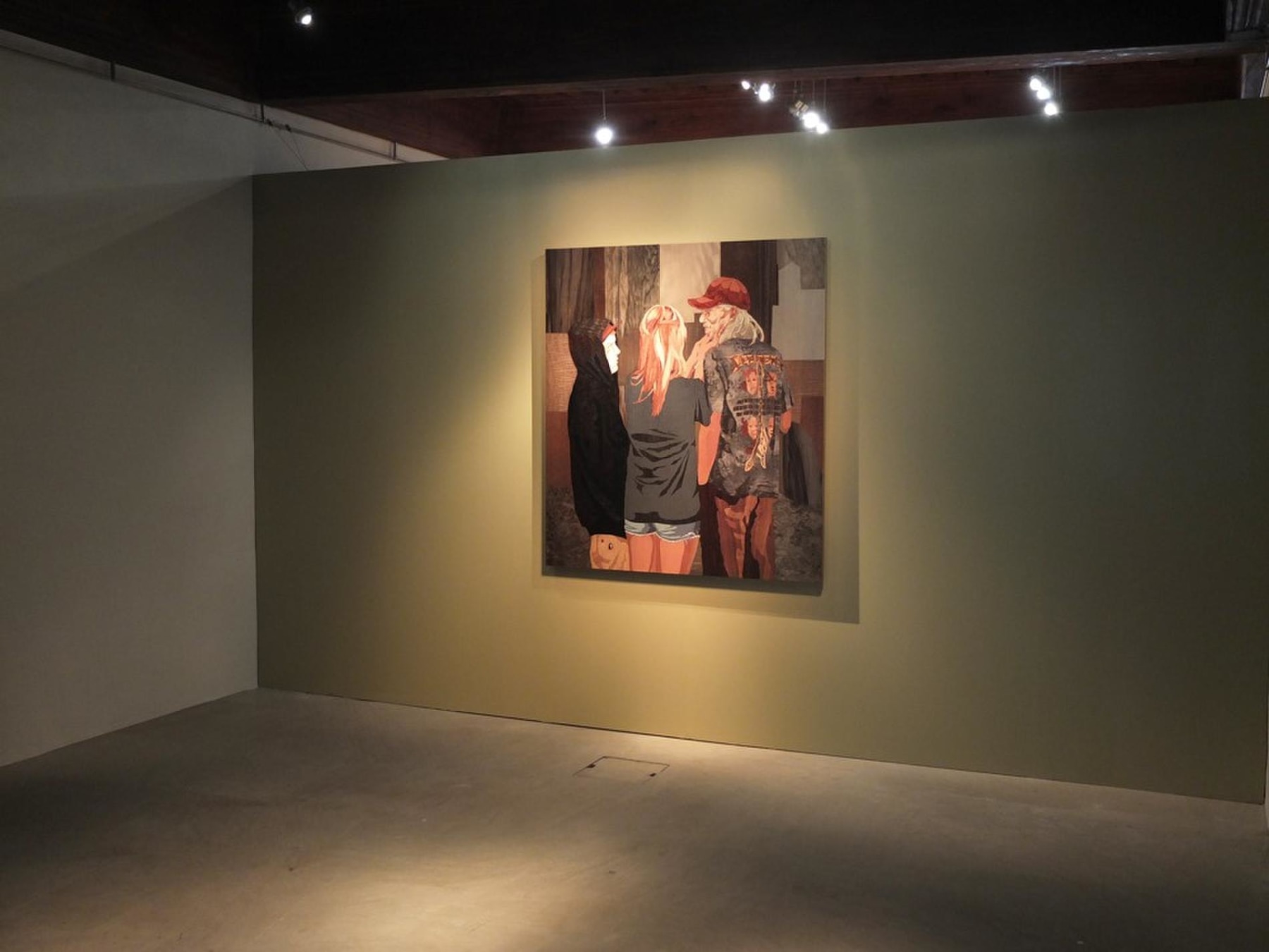 a dimly lit room with a light shining on an artwork depicting a group of three people
