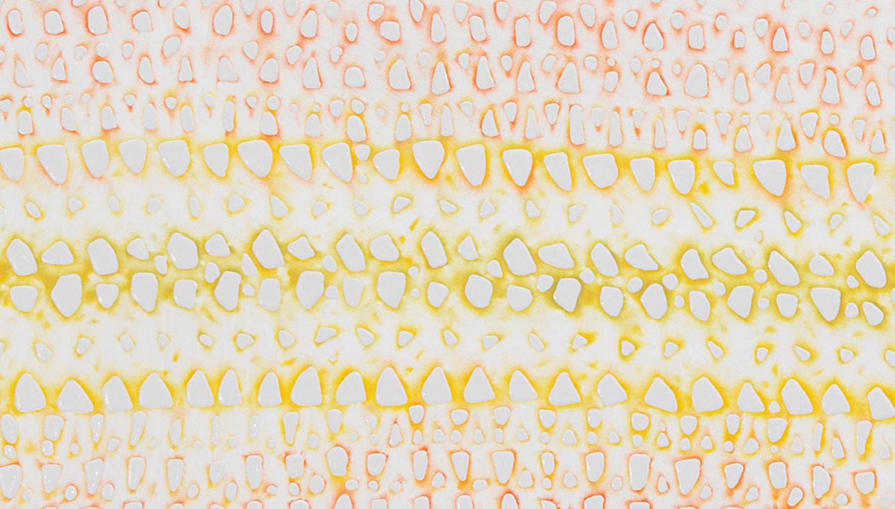 close up of fabric like pattern made up of white blots with a yellow and orange tint in the background