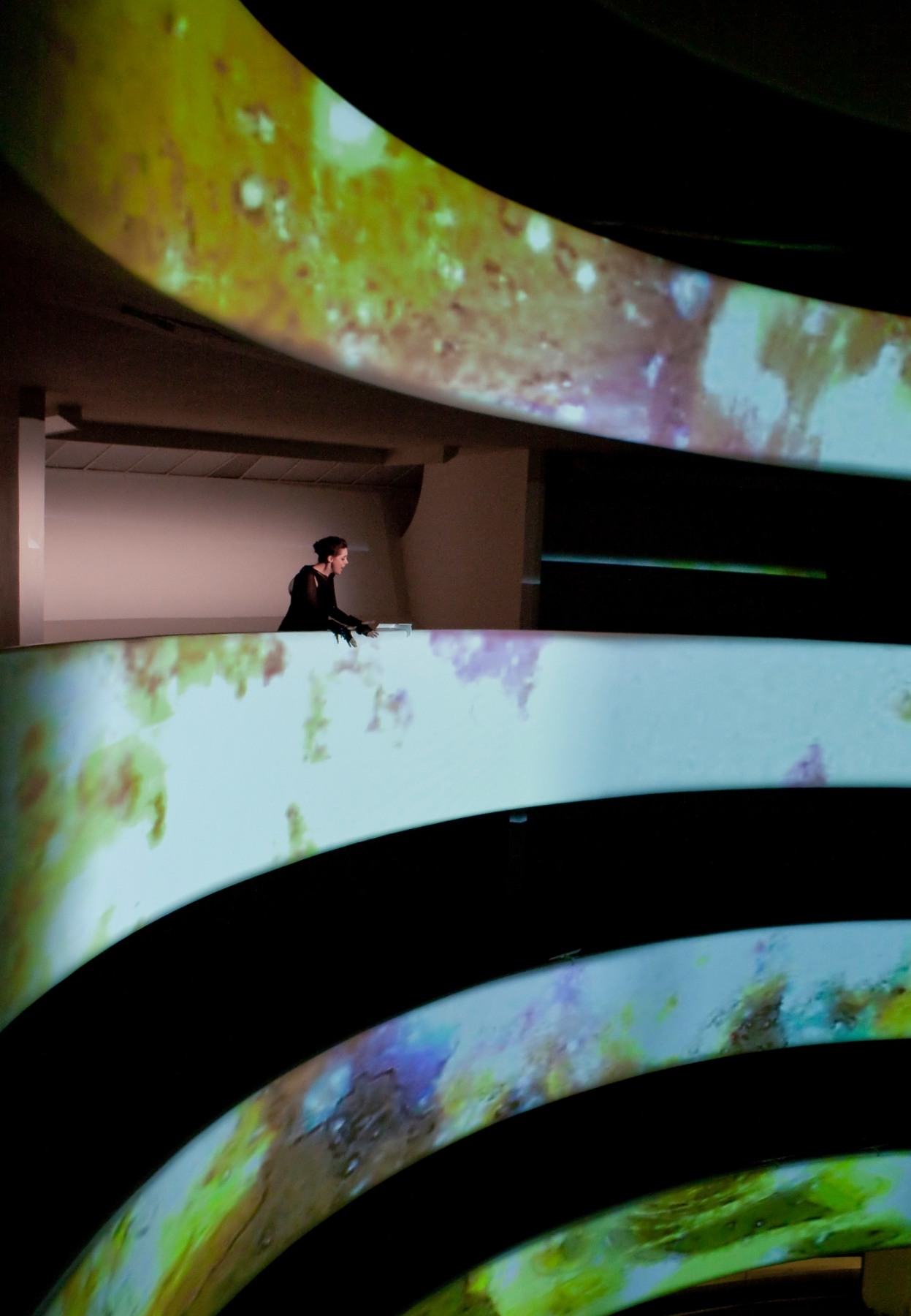 woman leaning on a balcony with images of color being projected on the walls
