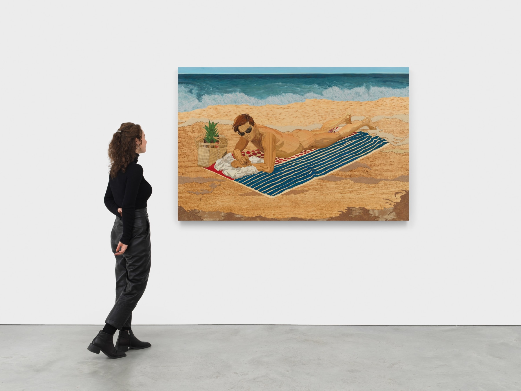 woman standing next to an engraving of a man lying nude on the beach