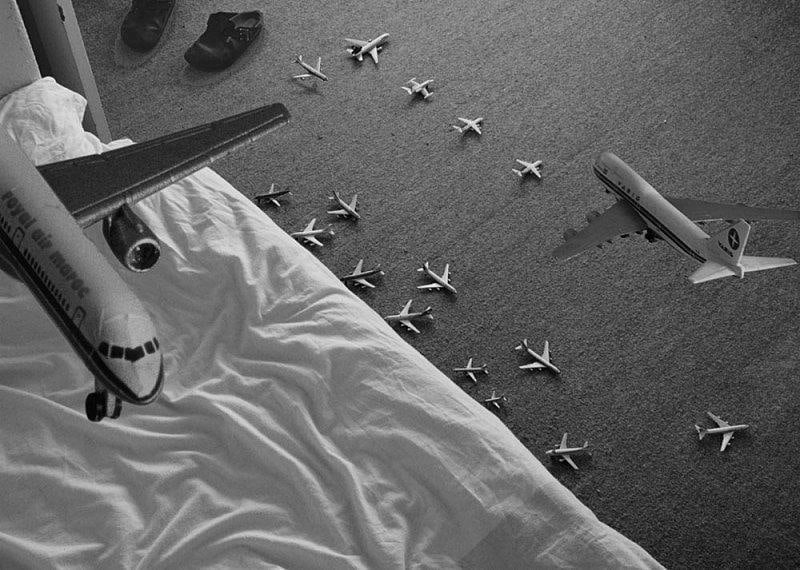 miniature airplanes placed next to a bed as well as flying around it