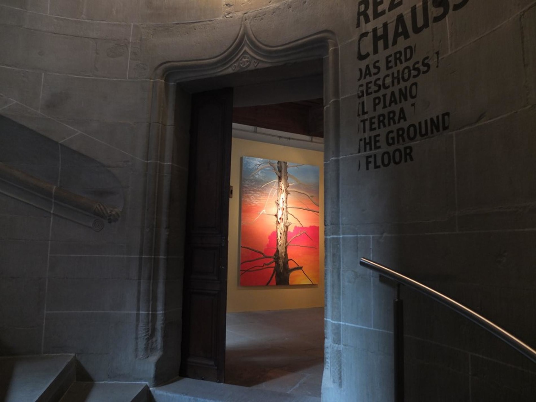 An open door revealing an artwork depicting a dead tree trunk