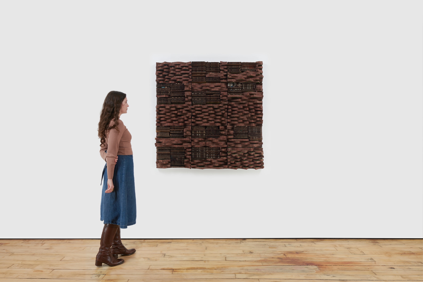 woman staring at brown square composed of woven brown electrical wires