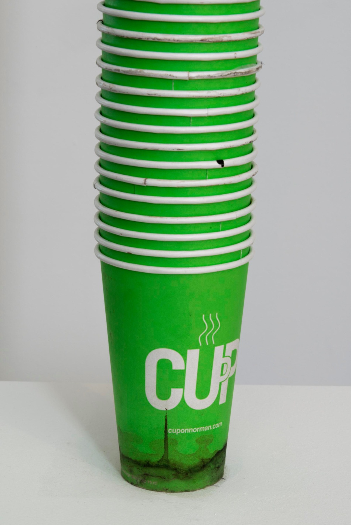 Detail shot of stacks of mostly green cups from pedestal to ceiling by SIMON EVANS&trade;.