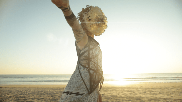 image of woman wearing a mask performing on the beach
