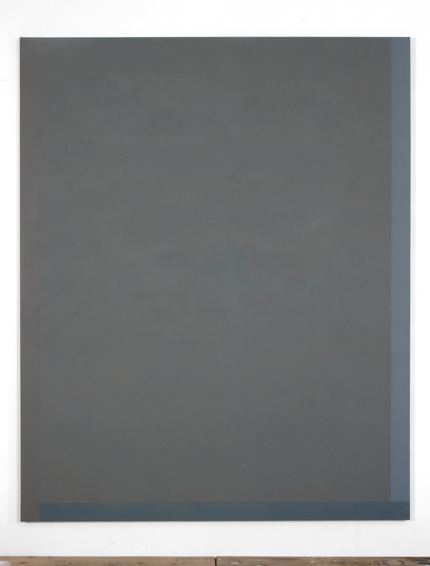 A painting with major portion of grey and two stripes of blue on the bottom and right edges of the canvas