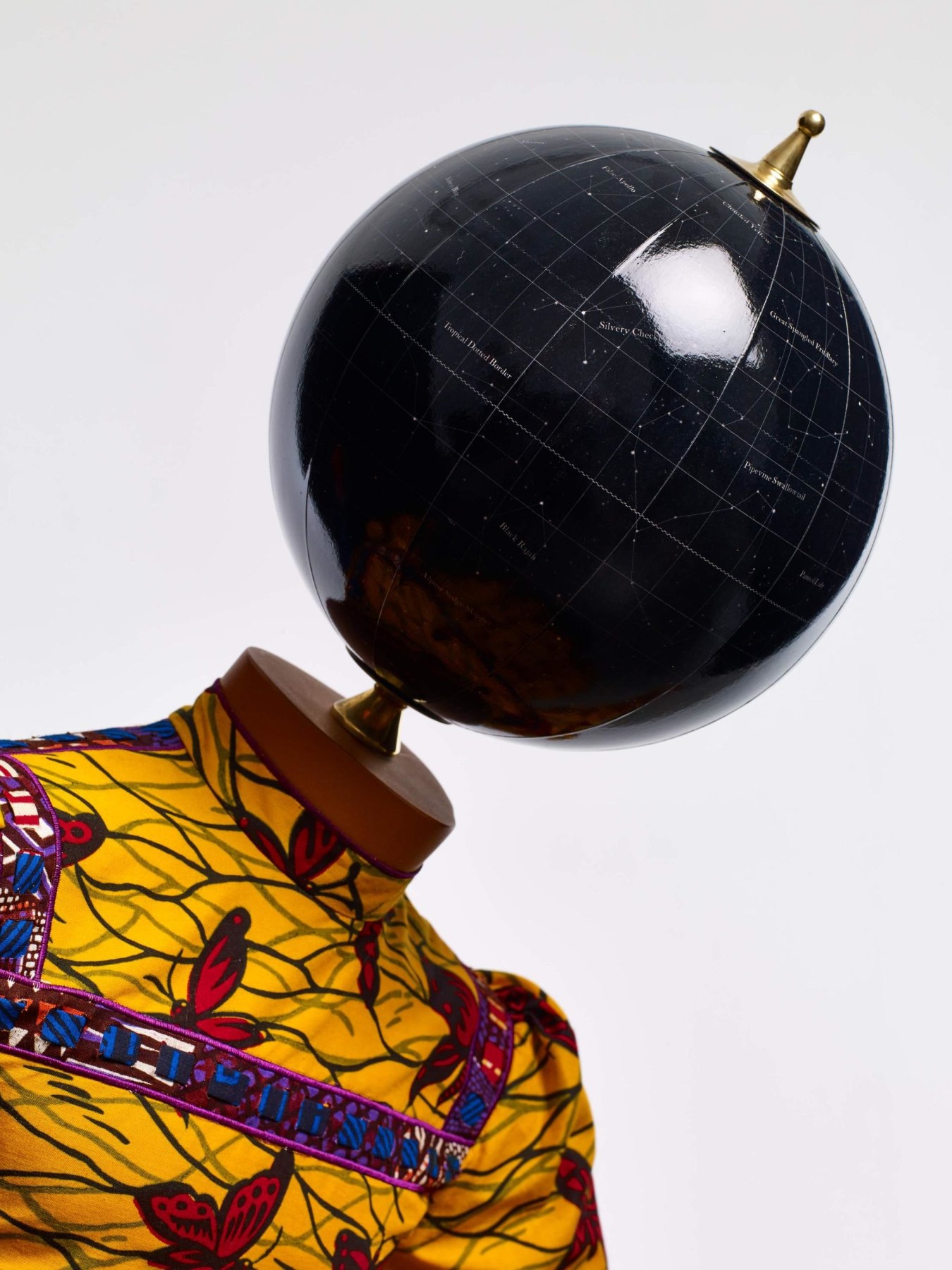 close up of a black globe acting as a head for a mannequin