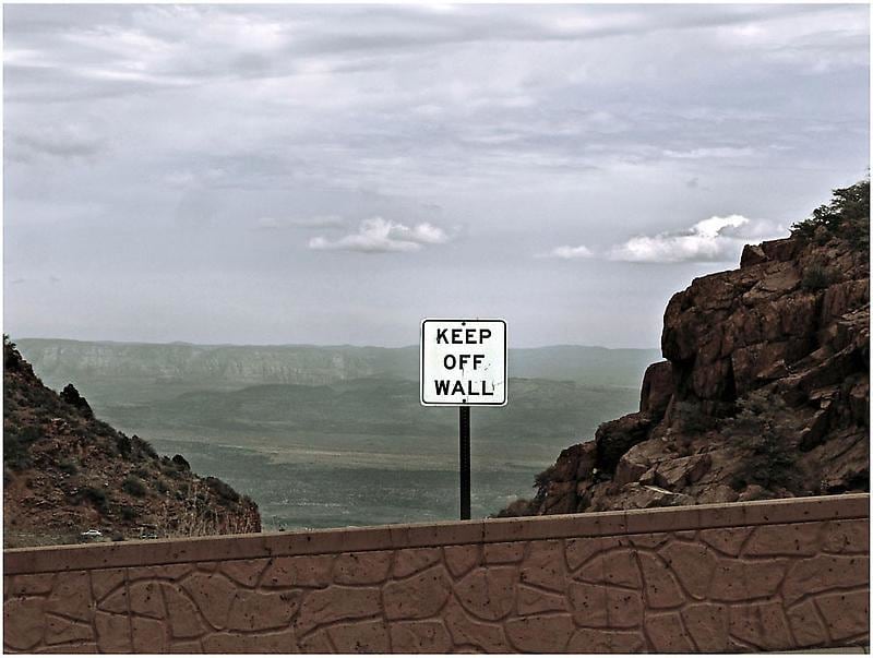 photograph of a sign that says &quot;keep off wall&quot; with the background of a landscape