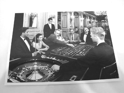 a group of well-dressed men and women gambling in a lavish setting