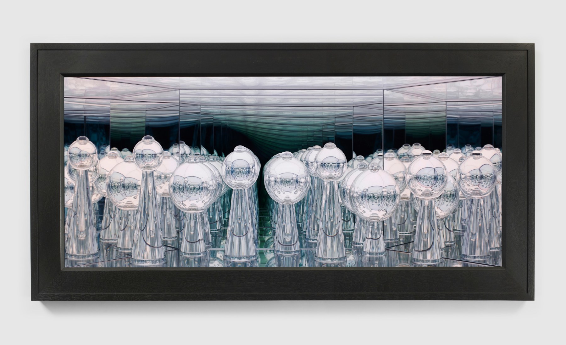 Handblown glass sculptures with reflective surfaces in a lit space framed behind a walnut frame