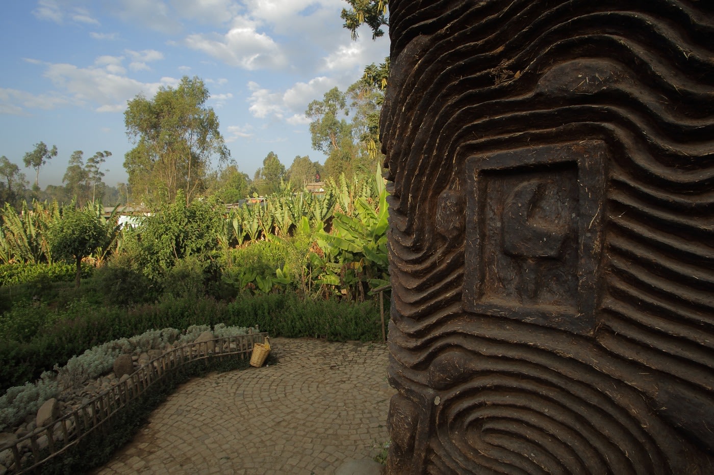close up of a carved wall with a green tropical garden in the background