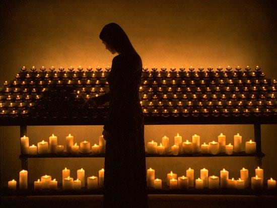 woman in front of several lit candles