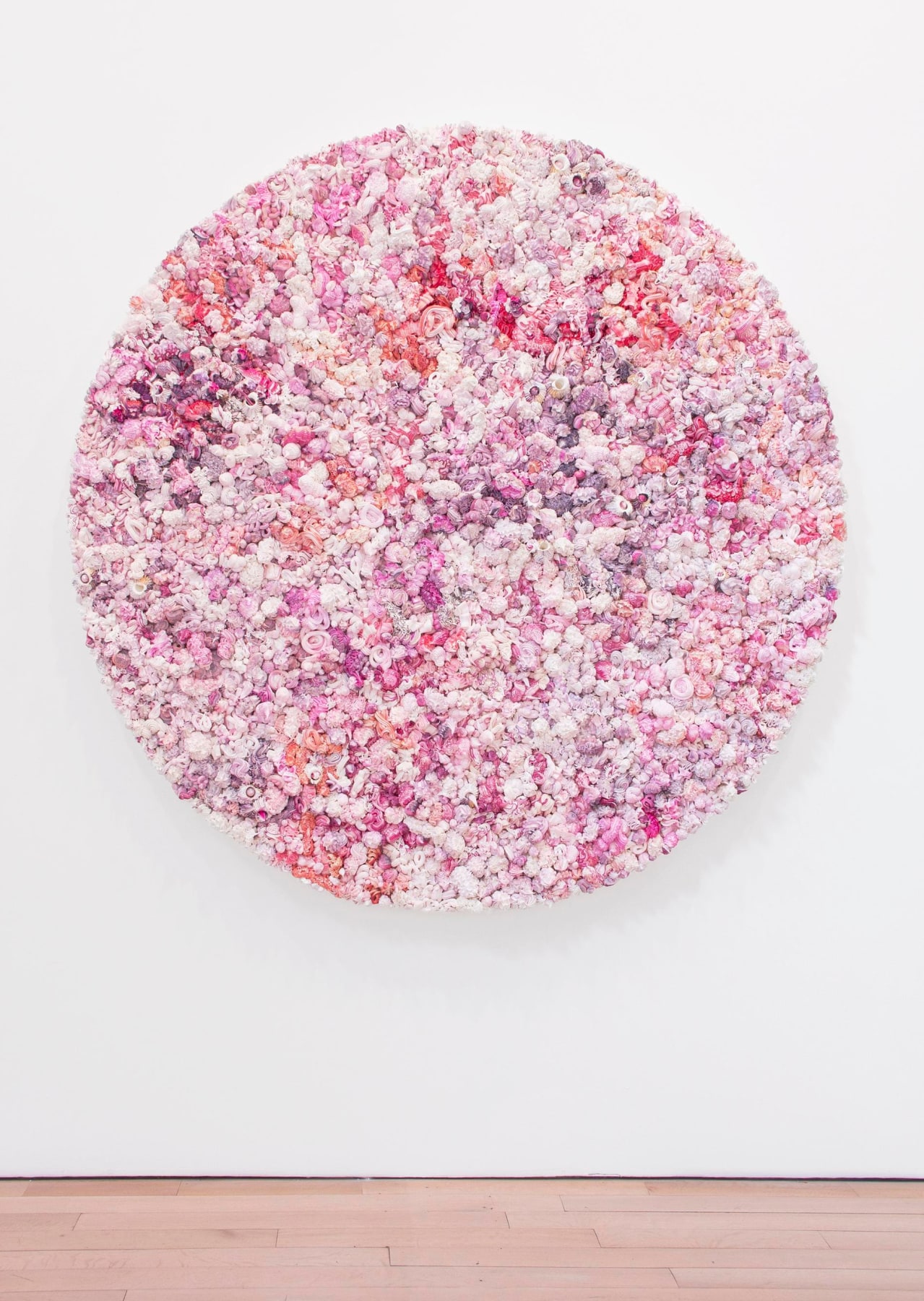A series of pink, purple, white and red whipped-cream-like dollops made of oil paint on a circular panel