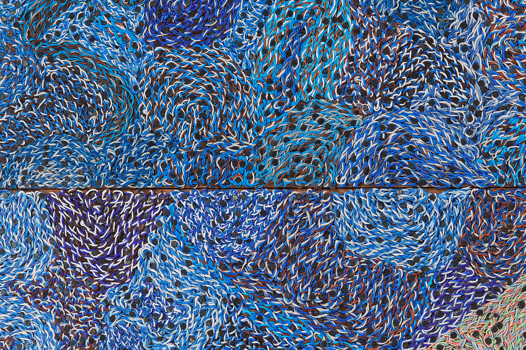 woven electrical wiring creating a blue, swirling, dotted surface