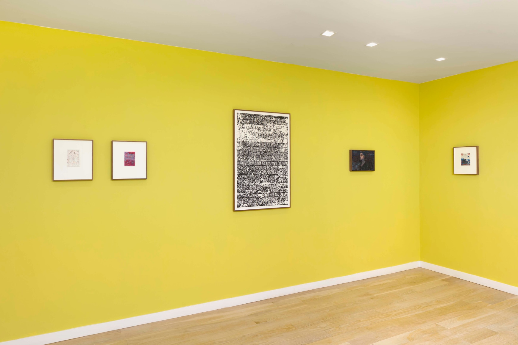 installation view of multiple works on paper and paintings in a yellow room