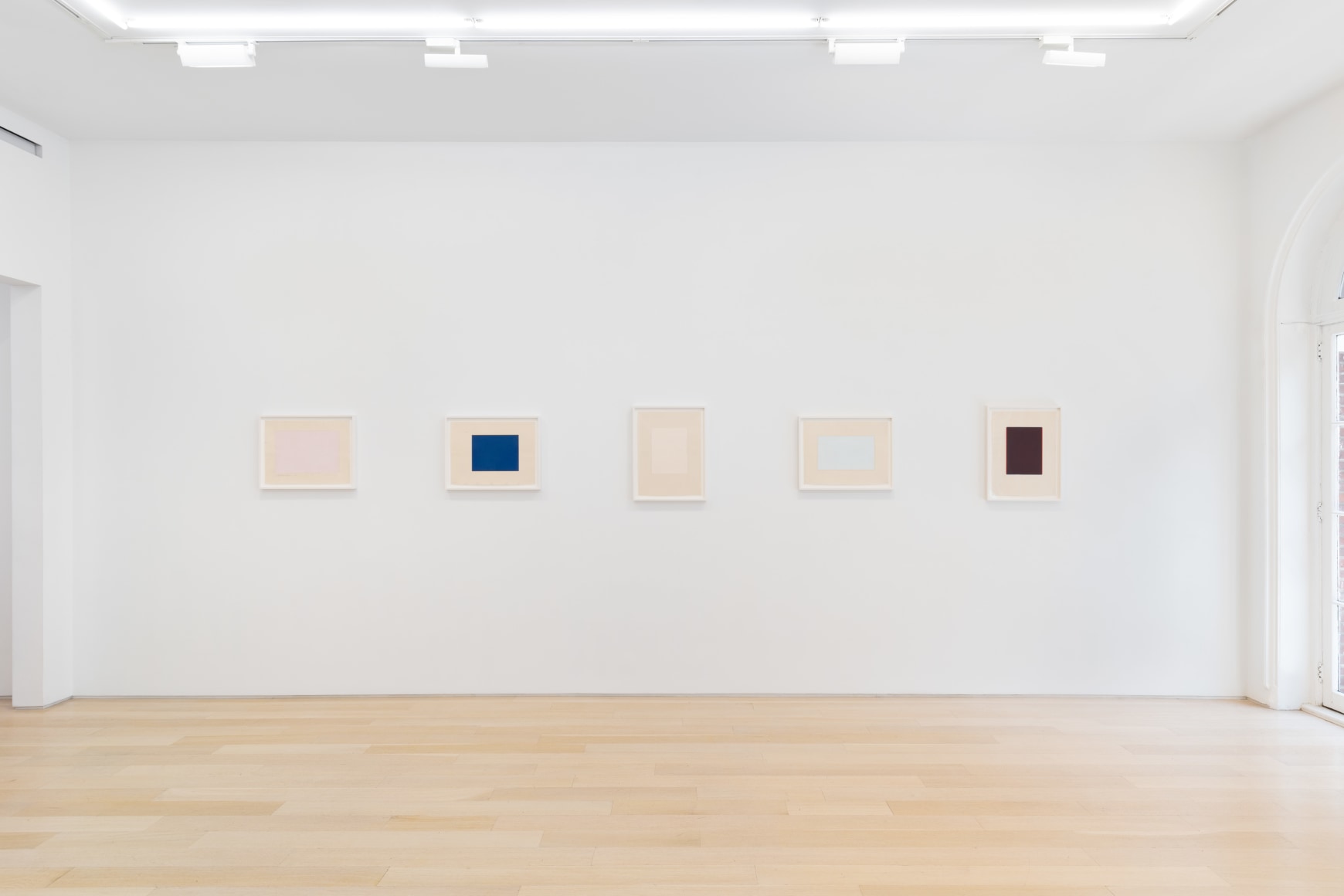 installation view of multiple works on paper in a white room