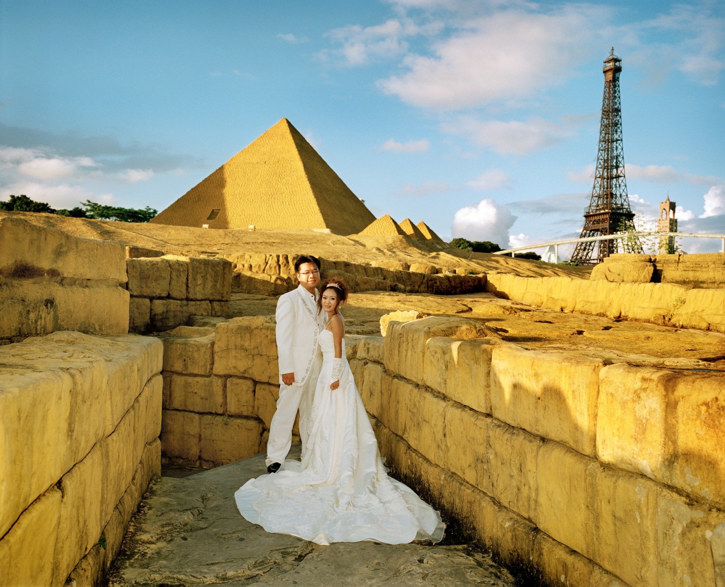 Reiner Riedler, Fake Holidays, Couple in wedding attire pose at Window of the World Theme Park, Shenzhen, China, 2008, Sous Les Etoiles Gallery